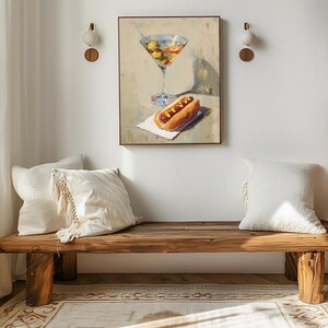 May include: A painting of a martini and a hot dog on a white napkin. The painting hangs above a wooden bench with two white pillows. The bench is made of rough-hewn wood and has a natural finish. Two wall sconces are mounted on the wall.