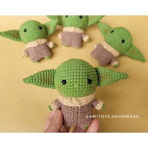May include: Four crocheted green and brown plush toys shaped like a character from the Star Wars franchise. The toys have large ears and big eyes. The text '@AMITOYS.HANDMADE' is visible in the bottom right corner of the image.