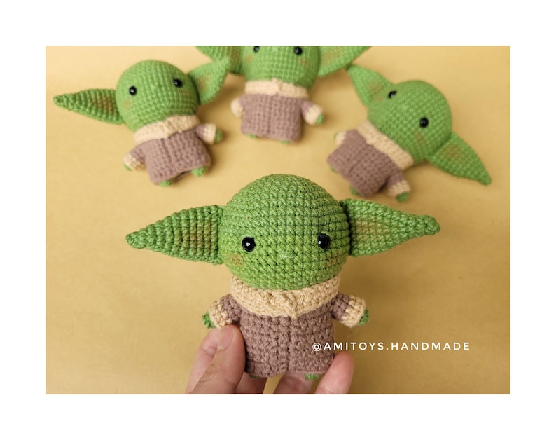 May include: Four crocheted green and brown plush toys shaped like a character from the Star Wars franchise. The toys have large ears and big eyes. The text '@AMITOYS.HANDMADE' is visible in the bottom right corner of the image.