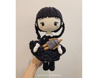 May include: A crocheted doll with black hair, a white dress, and a black and white dress. The doll is holding a smaller crocheted doll in its arms. The doll is wearing black shoes.