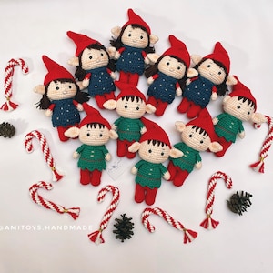 May include: A collection of 10 handmade crocheted elf ornaments. The elves are dressed in red, green, and blue clothing with white accents. The elves have white yarn for their faces and black yarn for their eyes and mouths. The elves are arranged in a circle on a white background.