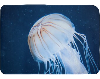 May include: A translucent white jellyfish with brown stripes on its bell, floating in a dark blue water tank.