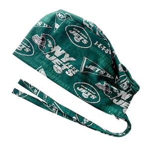 May include: A green and white New York Jets scrub cap. The cap features the team's logo, the words "New York Jets", and other football-related text. The cap has ties for securing it.