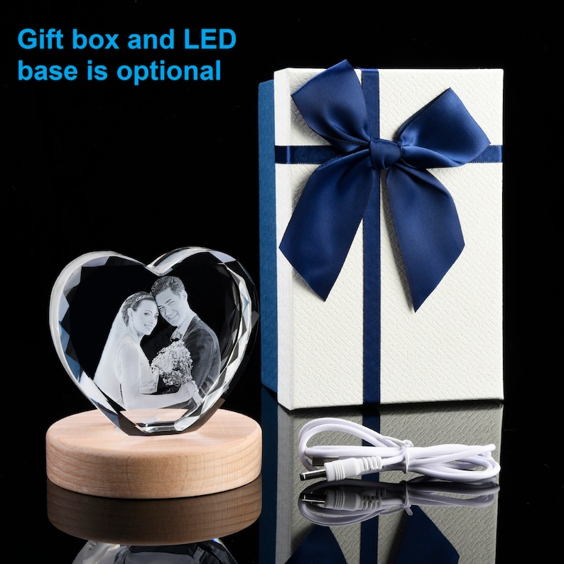 May include: A heart-shaped crystal with a 3D engraved image of a couple. The crystal is on a wooden base with a built-in LED light. A white gift box with a blue ribbon is included.