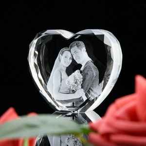 May include: A crystal heart-shaped paperweight with a 3D engraved image of a couple. The couple are dressed in formal attire and are holding a bouquet of flowers.
