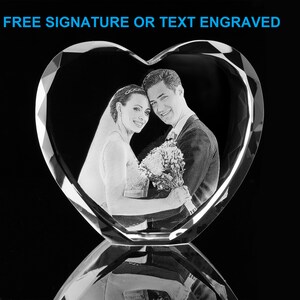 May include: A crystal heart-shaped paperweight with a 3D engraved image of a couple holding a bouquet of flowers. The text "FREE SIGNATURE OR TEXT ENGRAVED" is at the top of the image.
