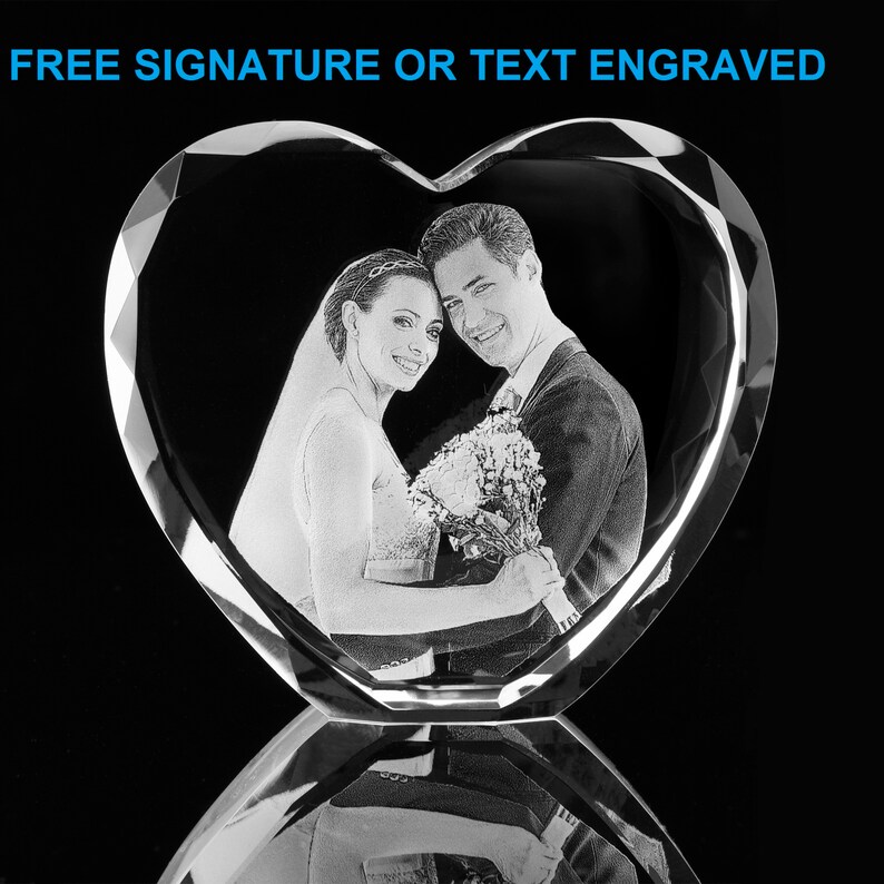 May include: A crystal heart-shaped paperweight with a 3D engraved image of a couple holding a bouquet of flowers. The text "FREE SIGNATURE OR TEXT ENGRAVED" is at the top of the image.