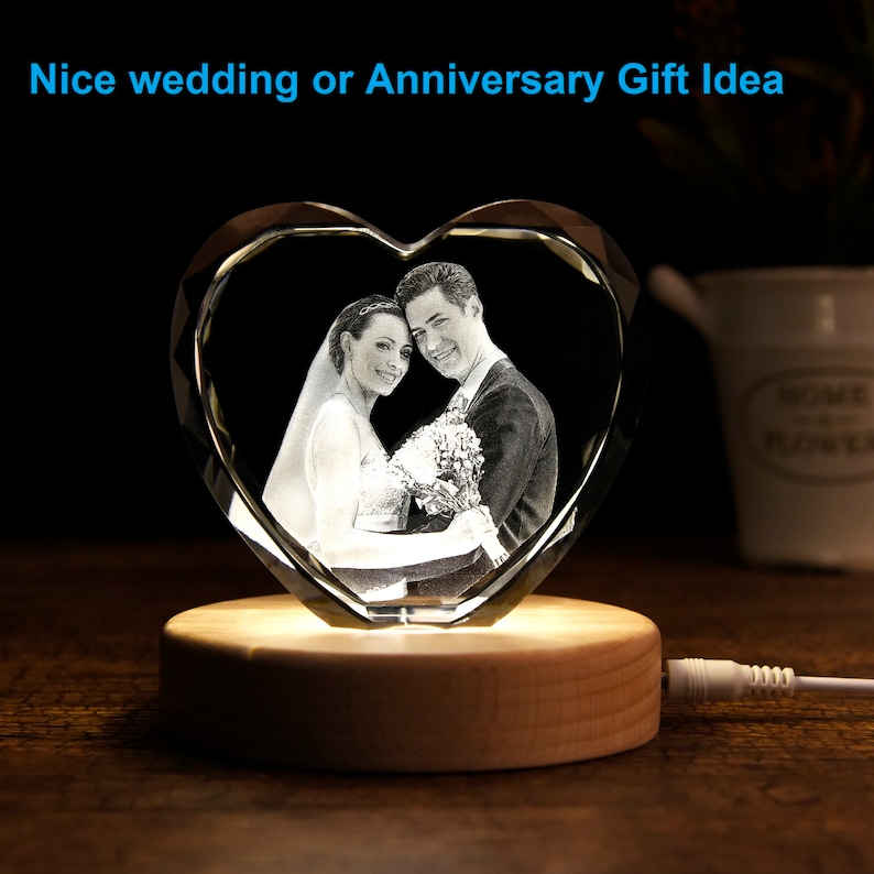 May include: A heart-shaped crystal with a laser-engraved image of a couple, illuminated by a light base. The crystal is on a wooden base with a cord.