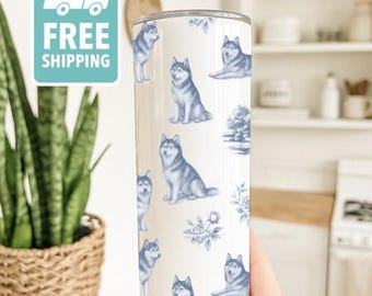 May include: A white tumbler featuring a repeating pattern of blue Siberian Huskies and floral accents. The tumbler is cylindrical and appears to be made of stainless steel. The words "FREE SHIPPING" are on a teal tag.