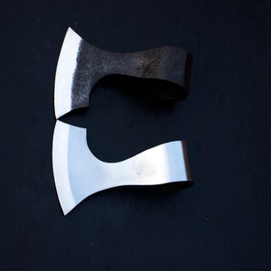 May include: Two small axes with wooden handles. The top axe has a black handle and a dull blade. The bottom axe has a silver handle and a shiny blade.