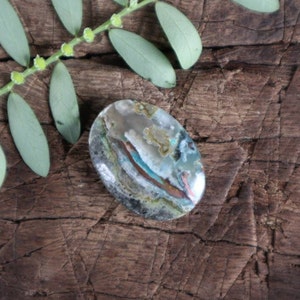 May include: A smooth, oval-shaped stone with a unique pattern of blue, green, brown, and white colors. The stone has a polished finish and is a natural gemstone.