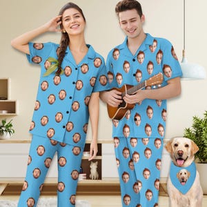 Könnte beinhalten: Ein Paar trägt passende blaue Pyjamas mit einem sich wiederholenden Muster eines Gesichts. Der Mann hält eine Ukulele und die Frau steht neben ihm. Ein Hund, der ein Bandana mit dem gleichen Muster trägt, sitzt im Vordergrund.