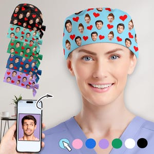 May include: A light blue surgical cap featuring a pattern of faces and red hearts. The cap is worn by a person in a blue scrub top. A stack of caps in various colors, including black, teal, green, navy, and purple, are also visible.