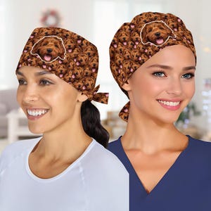 May include: Two brown scrub caps with a repeating pattern of a smiling dog face. One cap has a large dog face outlined in white. The caps are tied at the back. The background is blurred.
