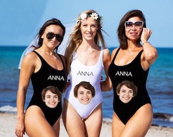Op de afbeelding: Drie vrouwen dragen zwarte en witte badpakken met de naam "ANNA" erop gedrukt. Elk badpak heeft een ander gezicht erop gedrukt.