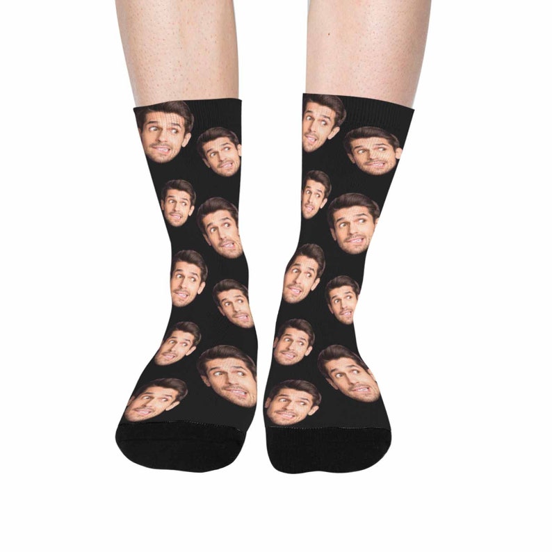 Op de afbeelding: Een paar zwarte sokken met een herhalend patroon van een mannengezicht. De sokken zijn gemaakt van een zacht, comfortabel materiaal en zijn perfect om elke outfit een persoonlijke touch te geven.