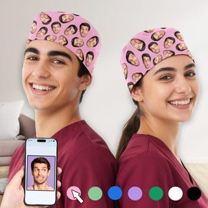 Könnte beinhalten: Zwei rosa OP-Hauben mit einem sich wiederholenden Muster von Gesichtern. Die Hauben werden von zwei Personen getragen, die weinrote OP-Kleidung tragen. Ein Telefon zeigt ein Gesicht mit Farboptionen darunter. Die Hauben sind ein lustiges, personalisiertes Accessoire.