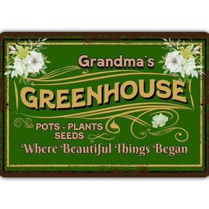 May include: A green sign with a brown border and white flowers. The sign says "Grandma's Greenhouse Pots - Plants Seeds Where Beautiful Things Began."