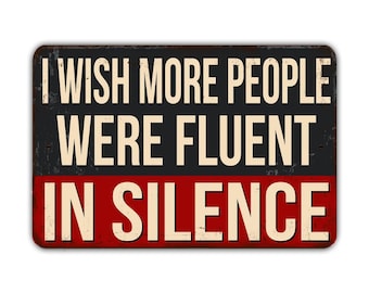 May include: A rusty metal sign with a red and black background. The sign reads "I wish more people were fluent in silence."