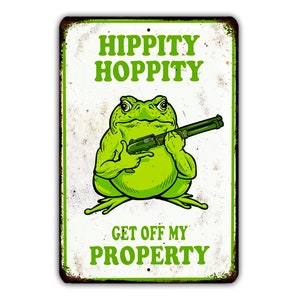 Może przedstawiać: Zielona żaba trzymająca strzelbę z napisem "Hippity Hoppity Get Off My Property" na białym tle z fakturą postarzanego metalu.