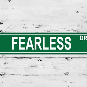 May include: Green street sign with white lettering that reads "FEARLESS DR".