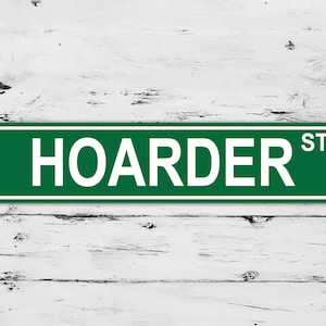May include: Green street sign with white lettering that reads "HOARDER ST".