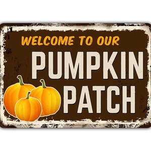 Puede incluir: Un letrero de metal marrón con un aspecto desgastado, con el texto "Welcome to our Pumpkin Patch" en letras blancas. Tres calabazas naranjas se representan en la esquina inferior izquierda.