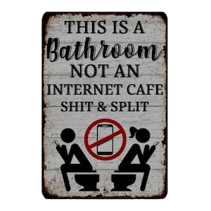 May include: A rectangular metal sign with a distressed finish. The sign reads "THIS IS A BATHROOM NOT AN INTERNET CAFE SHIT & SPLIT" in a mix of fonts. Below the text are two stick figures on toilets, with a crossed-out phone symbol.