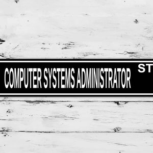 May include: Black and white sign with the text "COMPUTER SYSTEMS ADMINISTRATOR ST." on a white wooden background.