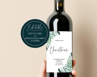 May include: A white wine bottle label with a green watercolor design of pine branches and holly. The label says "Pairs well with Christmas" and "An Anderson Family Christmas 12 | 25 | 24".
