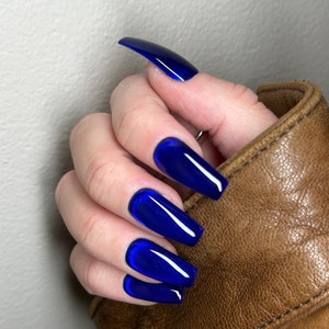 May include: Close-up of a hand with long, blue, coffin-shaped nails. The nails have a glossy finish and a slight shimmer.