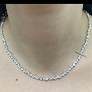 May include: A silver necklace with a delicate chain and a row of small, clear, baguette-shaped diamonds.