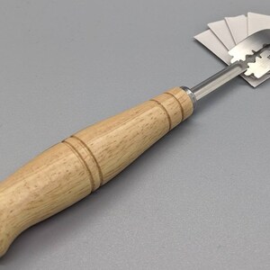 May include: A wooden handled tool with a stainless steel razor blade attached. The blade is labeled "Stainless Blade".