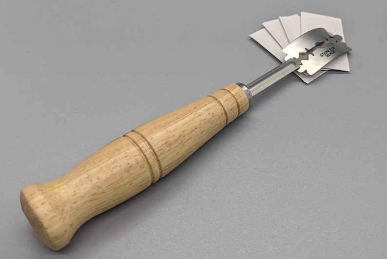 May include: A wooden handled tool with a stainless steel razor blade attached. The blade is labeled "Stainless Blade".