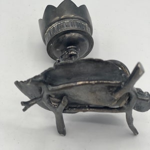 May include: A silver candlestick with a flower-shaped top and a base that resembles a bird perched on a branch.