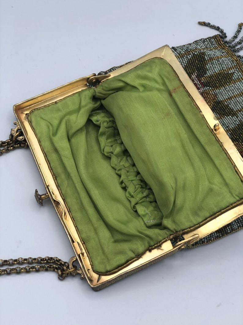 Peut inclure: Un sac &agrave; main vintage en perles avec une doublure en tissu vert et un cadre en m&eacute;tal dor&eacute;. Le sac &agrave; main a une bandouli&egrave;re en cha&icirc;ne et une frange en perles.