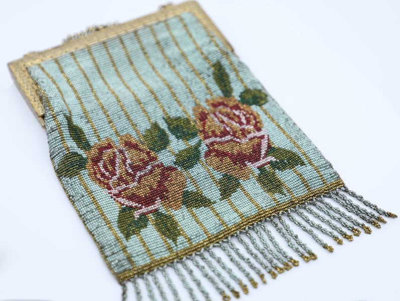Peut inclure: Un sac &agrave; main vintage en perles avec un fond ray&eacute; bleu et or et deux roses rouges et jaunes. Le sac &agrave; main a un fermoir en m&eacute;tal et une frange de perles.