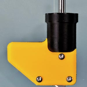 Puede incluir: Una herramienta de plástico amarilla y negra con una cuchilla de metal. La herramienta tiene un mango con una varilla de metal que se extiende desde la parte superior. La cuchilla es visible en la parte inferior de la herramienta.