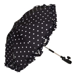 May include: Black and white polka dot stroller umbrella with a ruffled trim and a silver metal handle. The umbrella has a black clip to attach to a stroller.