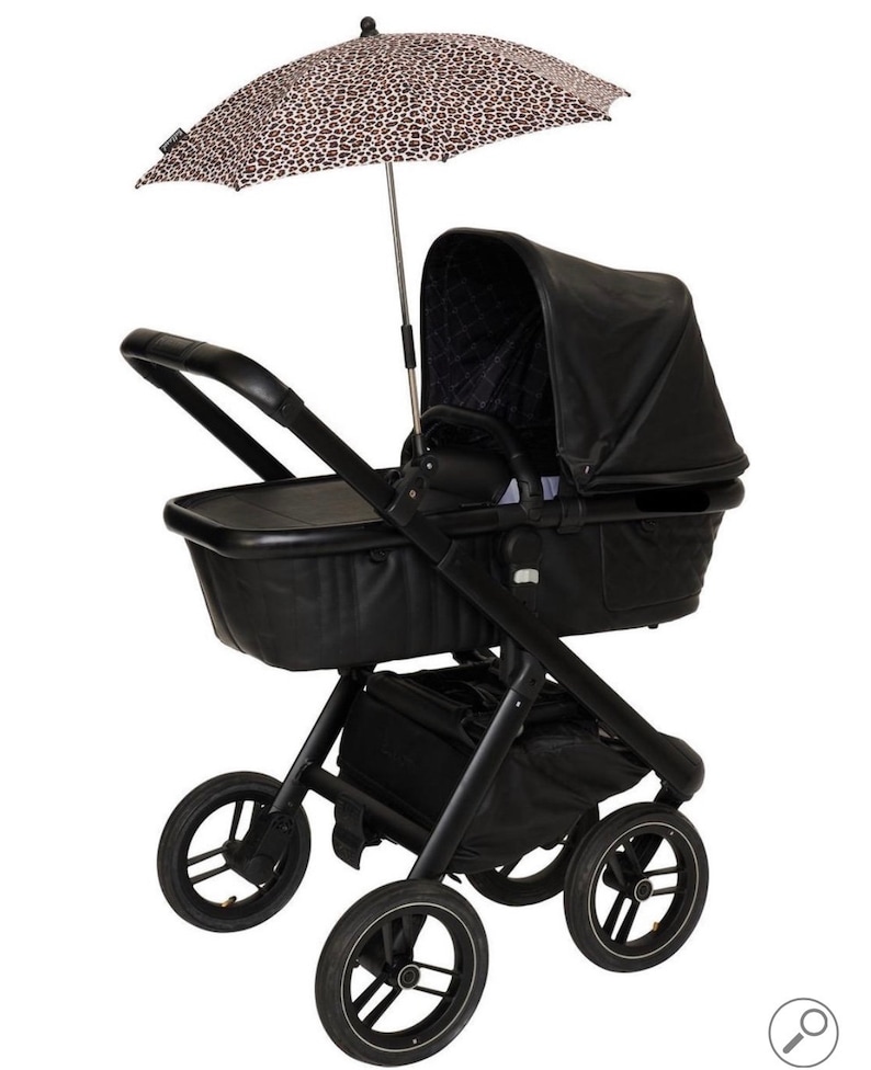 May include: A black stroller with a black leatherette bassinet and a leopard print sunshade. The stroller has four wheels and a storage basket.