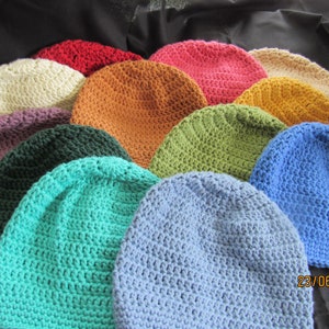 May include: A collection of crocheted beanies in various colors, including red, orange, pink, green, and blue. The hats are arranged in a circular pattern, showcasing the handmade texture and diverse color palette. The date "23/06/2023" is visible on the bottom right.