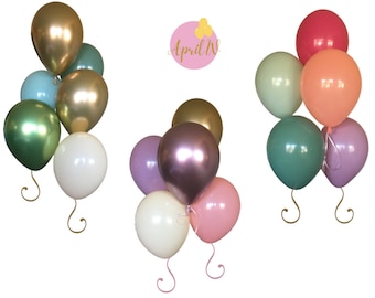 Può includere: Tre set di palloncini in diverse combinazioni di colori. Il primo set ha palloncini dorati, verdi, bianchi e blu. Il secondo set ha palloncini dorati, viola, bianchi e rosa. Il terzo set ha palloncini rossi, arancioni, verdi e verde chiaro. Tutti i palloncini hanno un laccio di torsione dorato.
