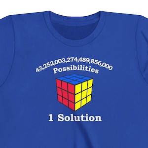 May include: A blue t-shirt with a white graphic of a Rubik's Cube and the text "43,252,003,274,489,856,000 Possibilities 1 Solution".