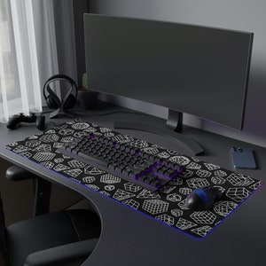 May include: A black and white geometric patterned mousepad with a black keyboard and a black and purple mouse on a black desk with a computer monitor.