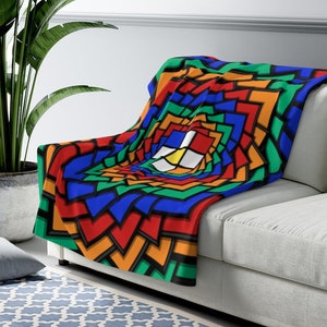 May include: A colorful throw blanket with a geometric pattern of squares and triangles in shades of red, orange, yellow, green, blue, and black. The pattern creates a swirling, optical illusion effect.