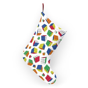 Może przedstawiać: Biała świąteczna skarpeta z wzorem kolorowych kostek Rubika.