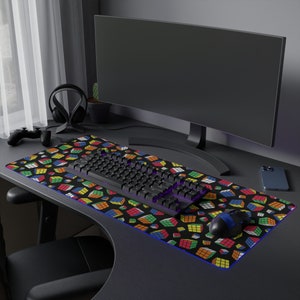 May include: A black computer keyboard with a colorful Rubik's Cube pattern mouse pad. The mouse pad has a blue border and a black computer mouse is on the pad.