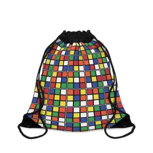 Puede incluir: Una bolsa de cordón negro con un patrón de cubo de Rubik colorido. La bolsa tiene un cordón de ajuste negro y correas negras.