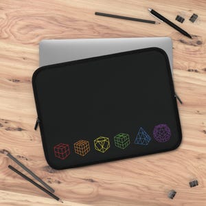 May include: Black laptop sleeve with a series of colourful geometric shapes. The shapes include cubes, a cube, a diamond, a cube, a pyramid, and a sphere. The sleeve is rectangular with a zip closure.