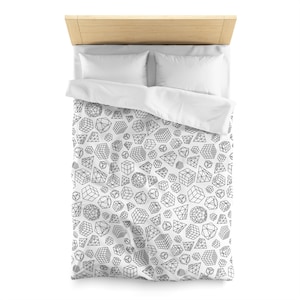 以下が含まれることがあります： 白地に黒と白の幾何学模様が施されたデュベカバー。立方体、球体、ピラミッドの模様です。